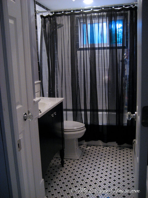 A sheer black shower curtain hung in a victorian style bathroom