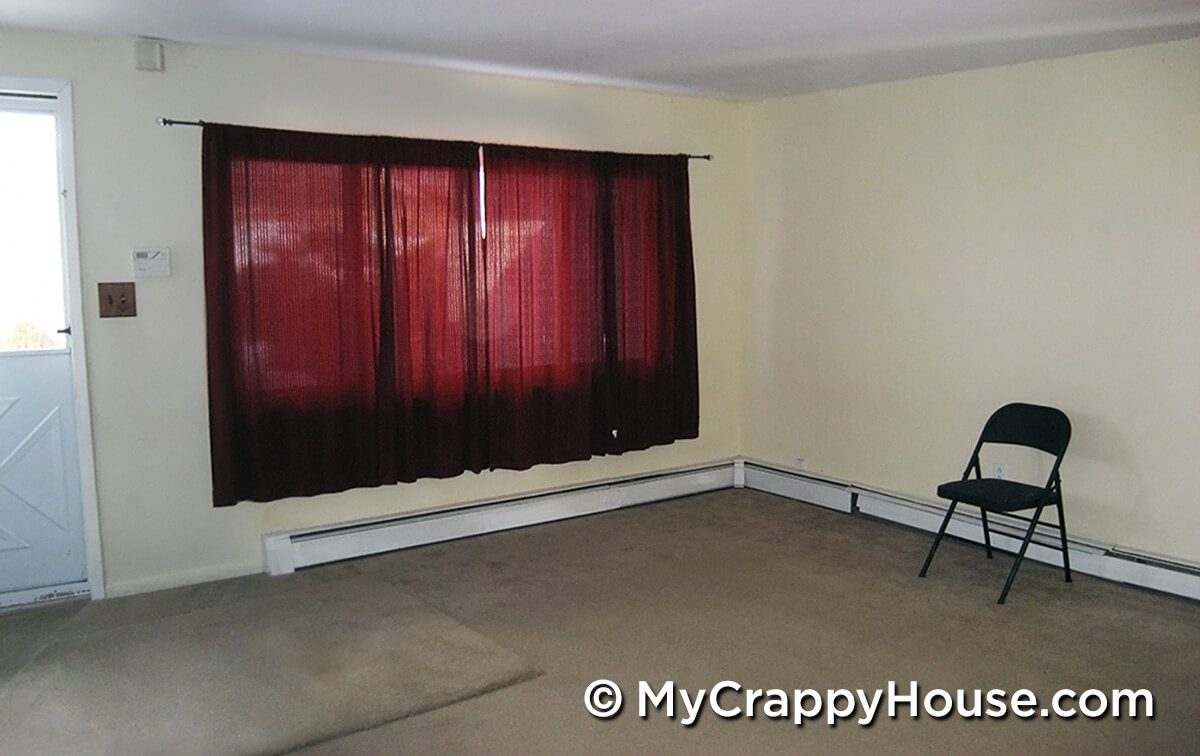 Living room with window, red curtains, and folding chair