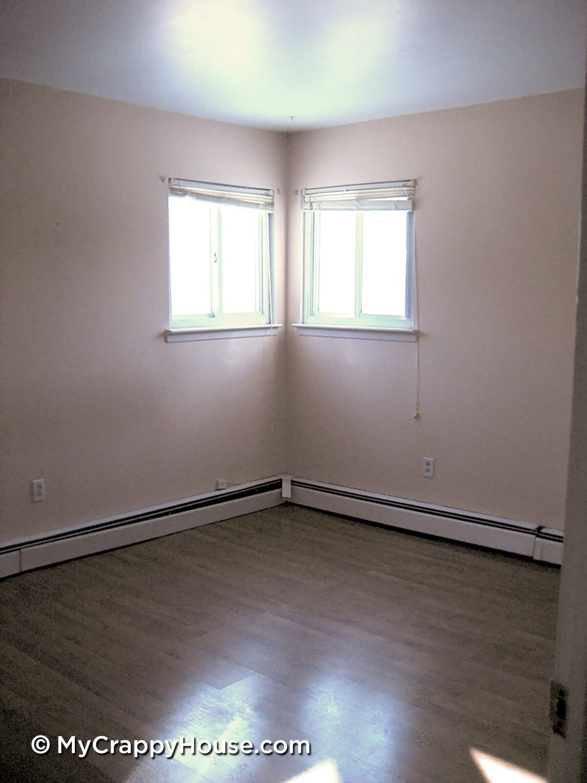 Empty room with peach walls and two windows in the corner