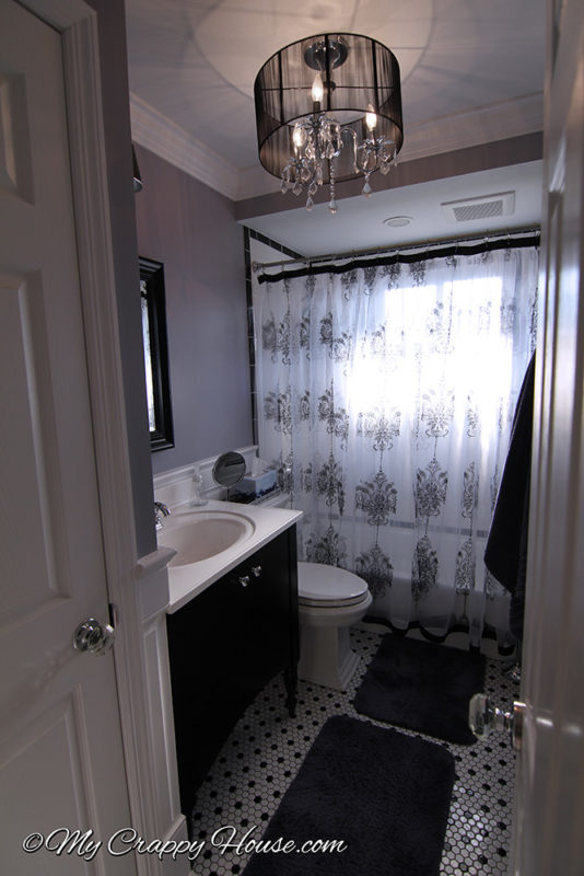 Picture of a victorian style bathroom with a hand made shower curtain, chandelier, tiny hexagon tile floor, purple walls