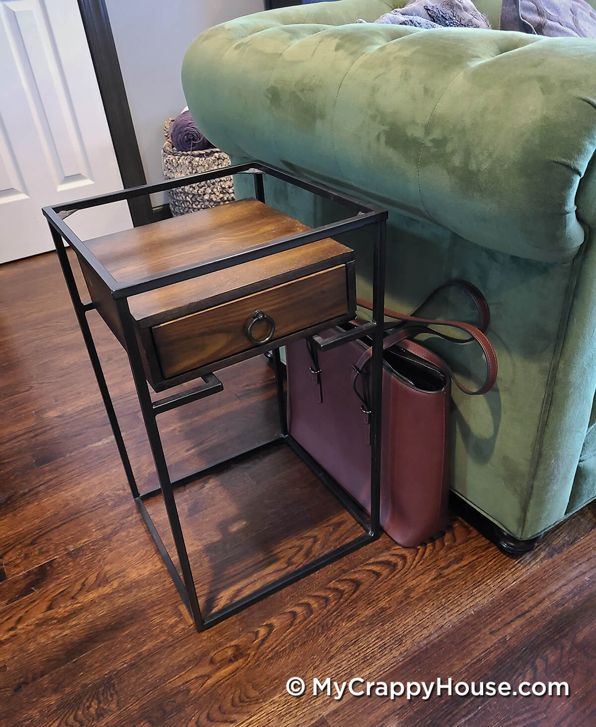 Metal and wood end table next to green couch