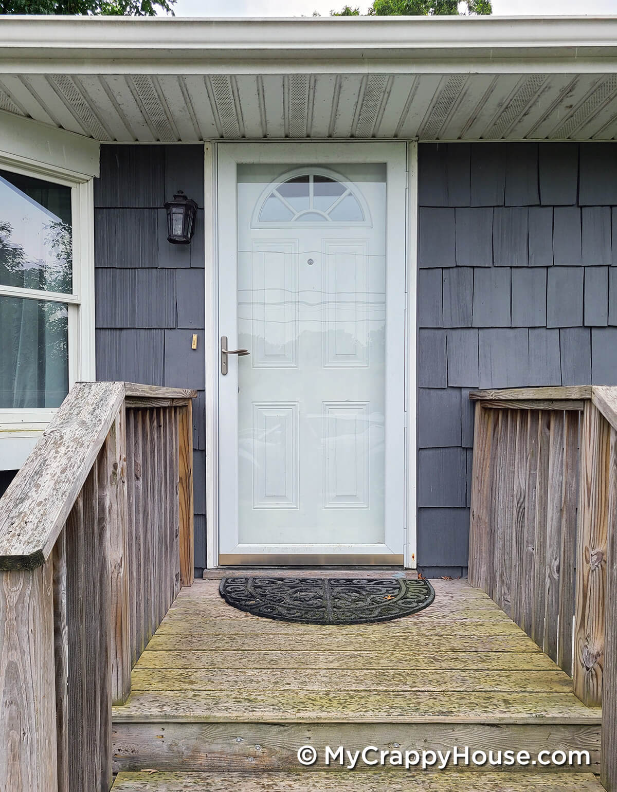 White front door on gray house with pressure treated wood front steps