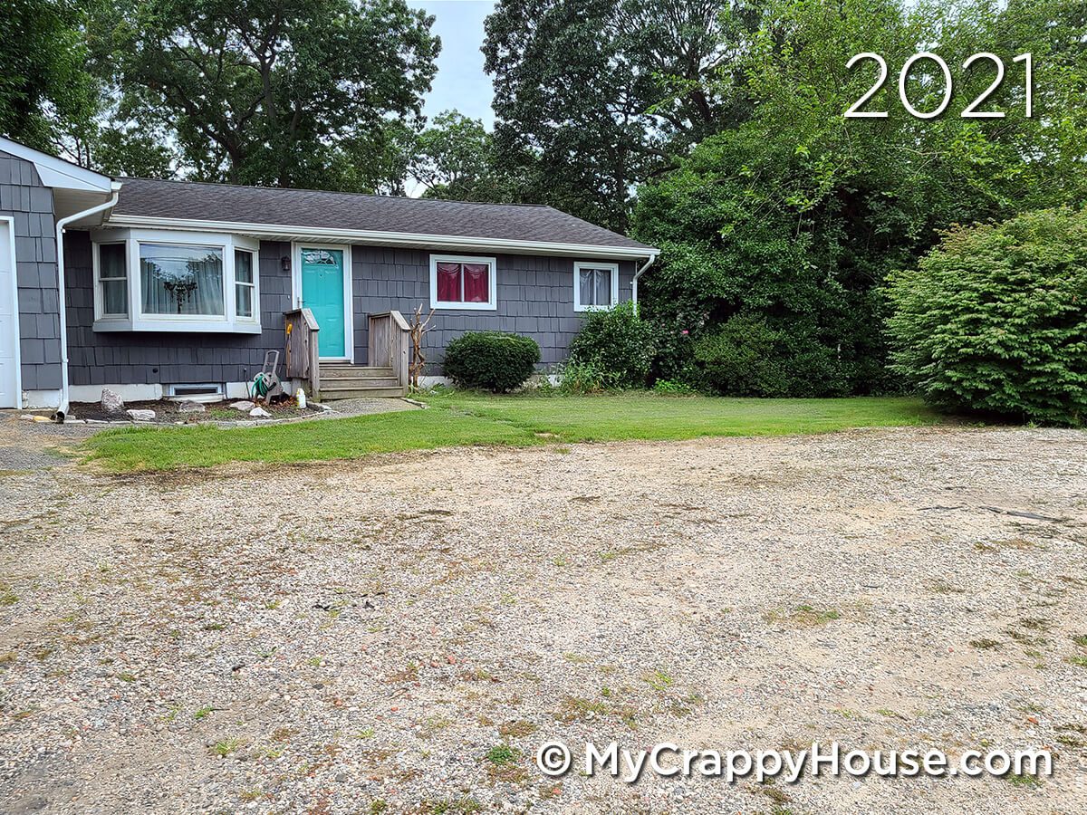 Gray ranch house with Tiffany blue door and crappy gravel driveway