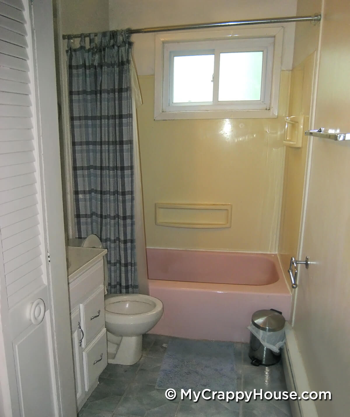 Bathroom with pink tub, yellow walls, blue floor and shower curtain. Super ugly.
