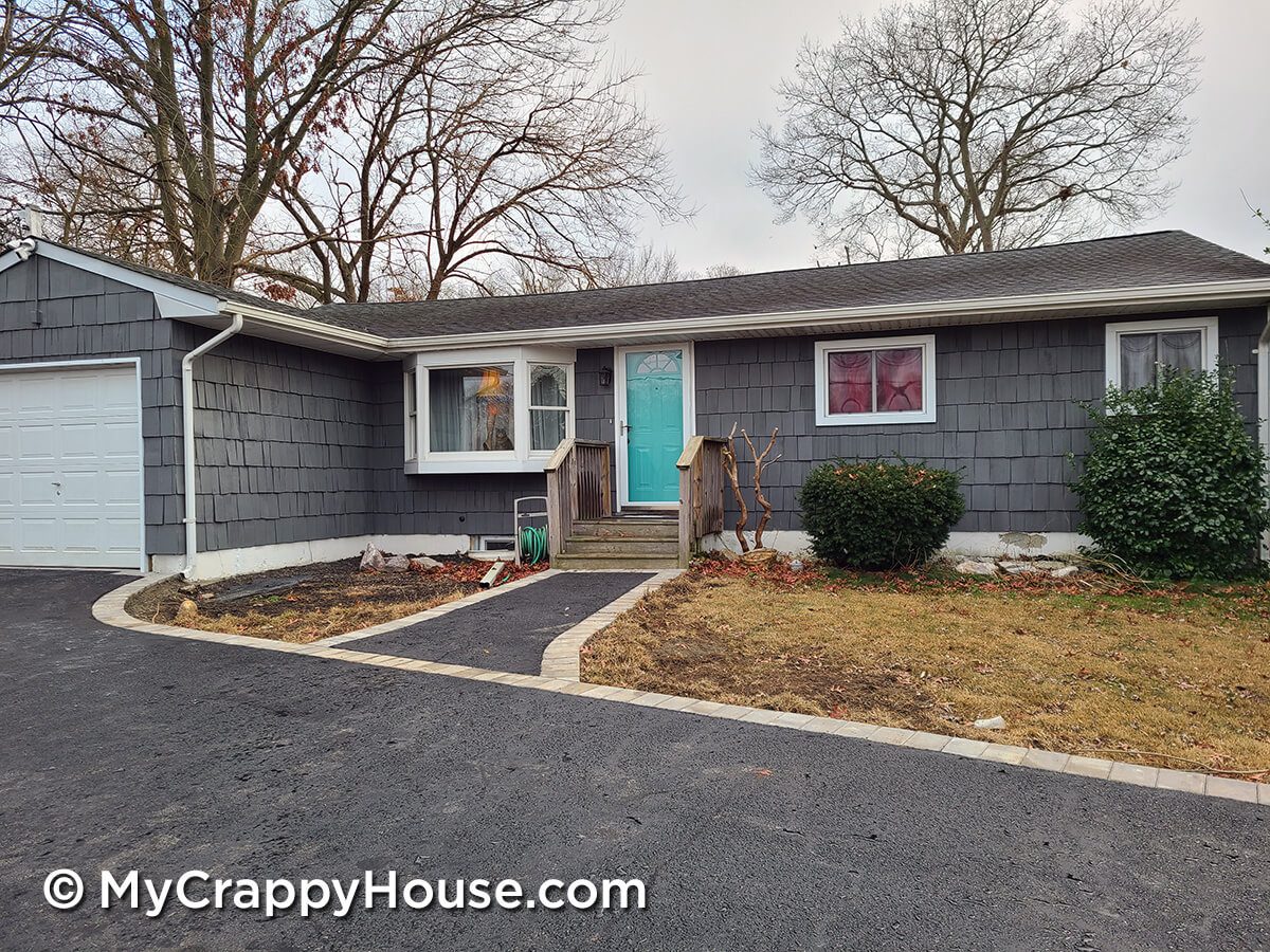 Gray house with Tiffany blue door and asphalt driveway with recessed flush pavers edging