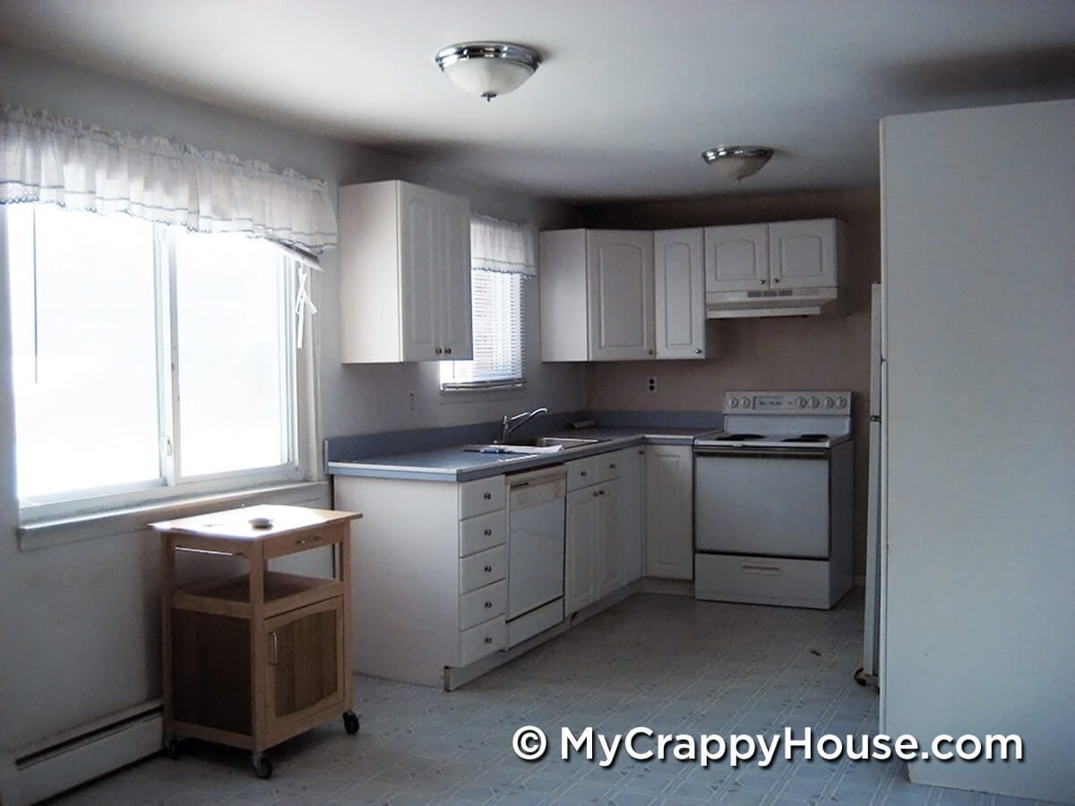 Gross kitchen with damaged cabinets and old white appliances