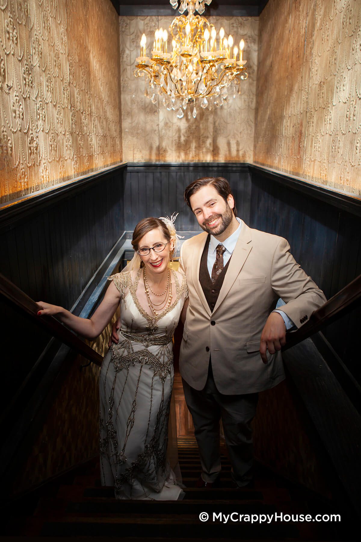 1920s theme bride and groom on stairs under chandelier