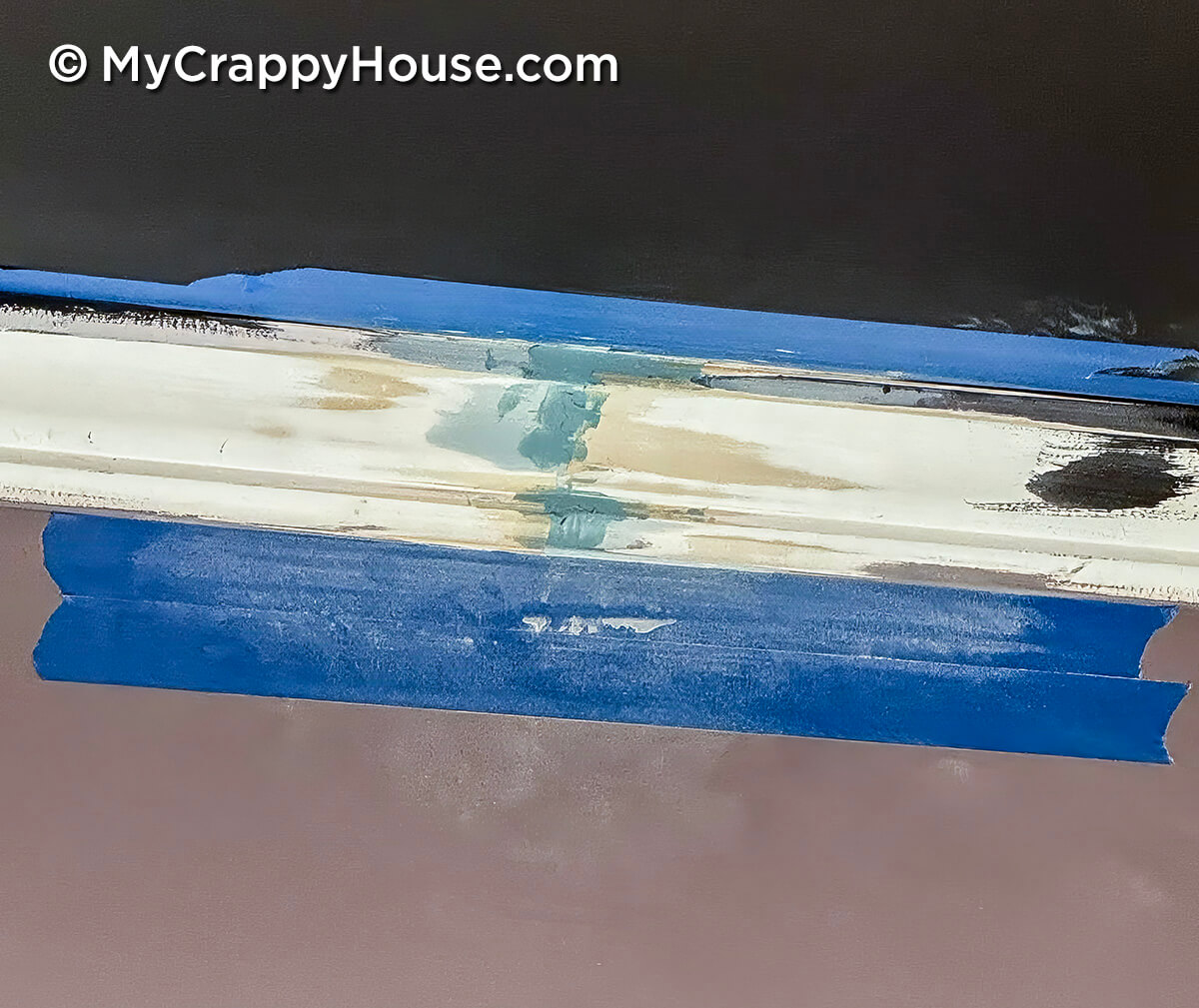 Crown molding seam patched with filler and Bondo, taped off with painter’s tape showing repair work before sanding and painting in DIY project