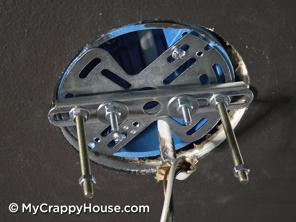 Universal mounting bracket installed on ceiling electrical box with extended bolts and spacers for hanging light fixture