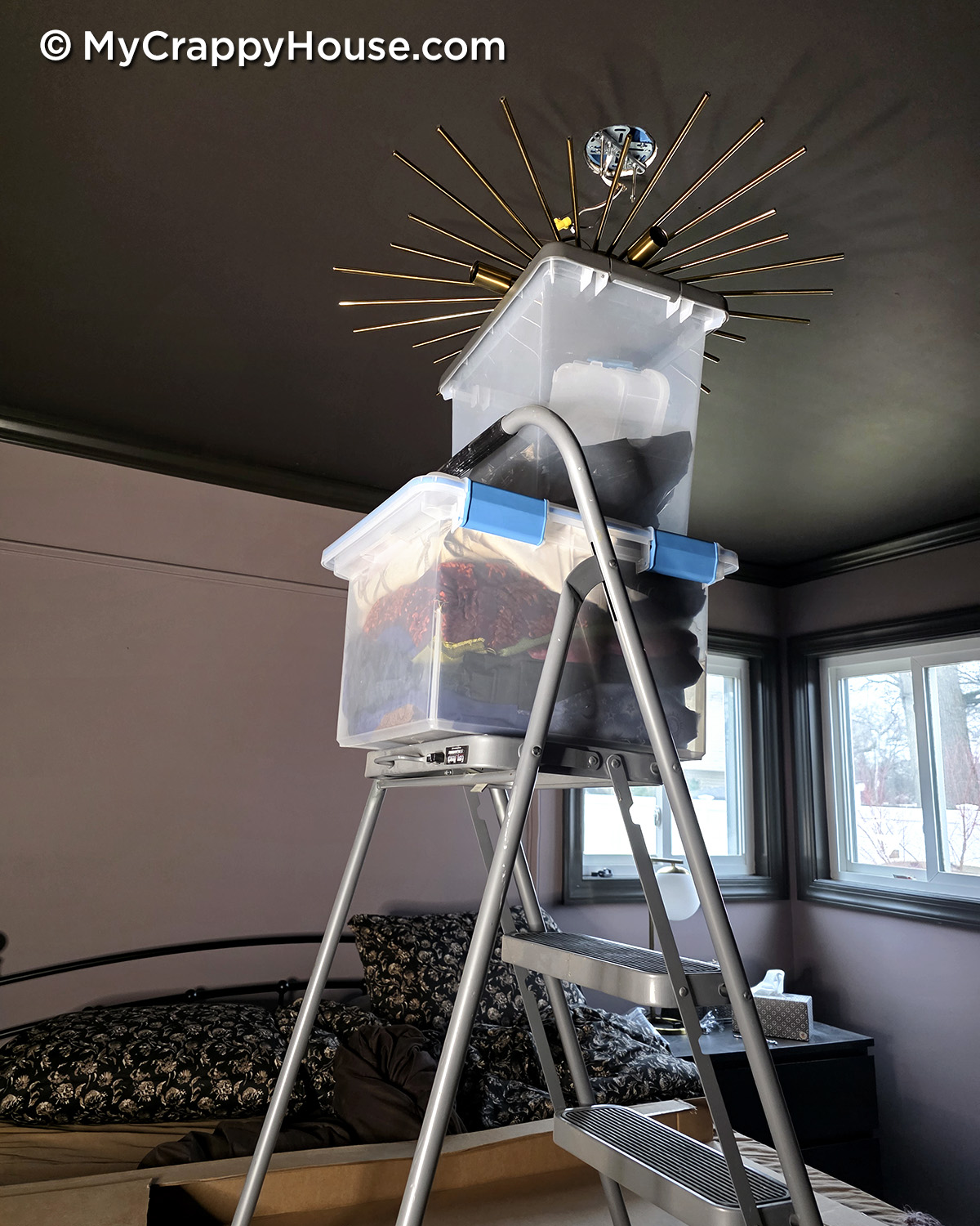 DIY scaffold made from step ladder and stacked storage bins used to support a heavy ceiling light fixture during installation
