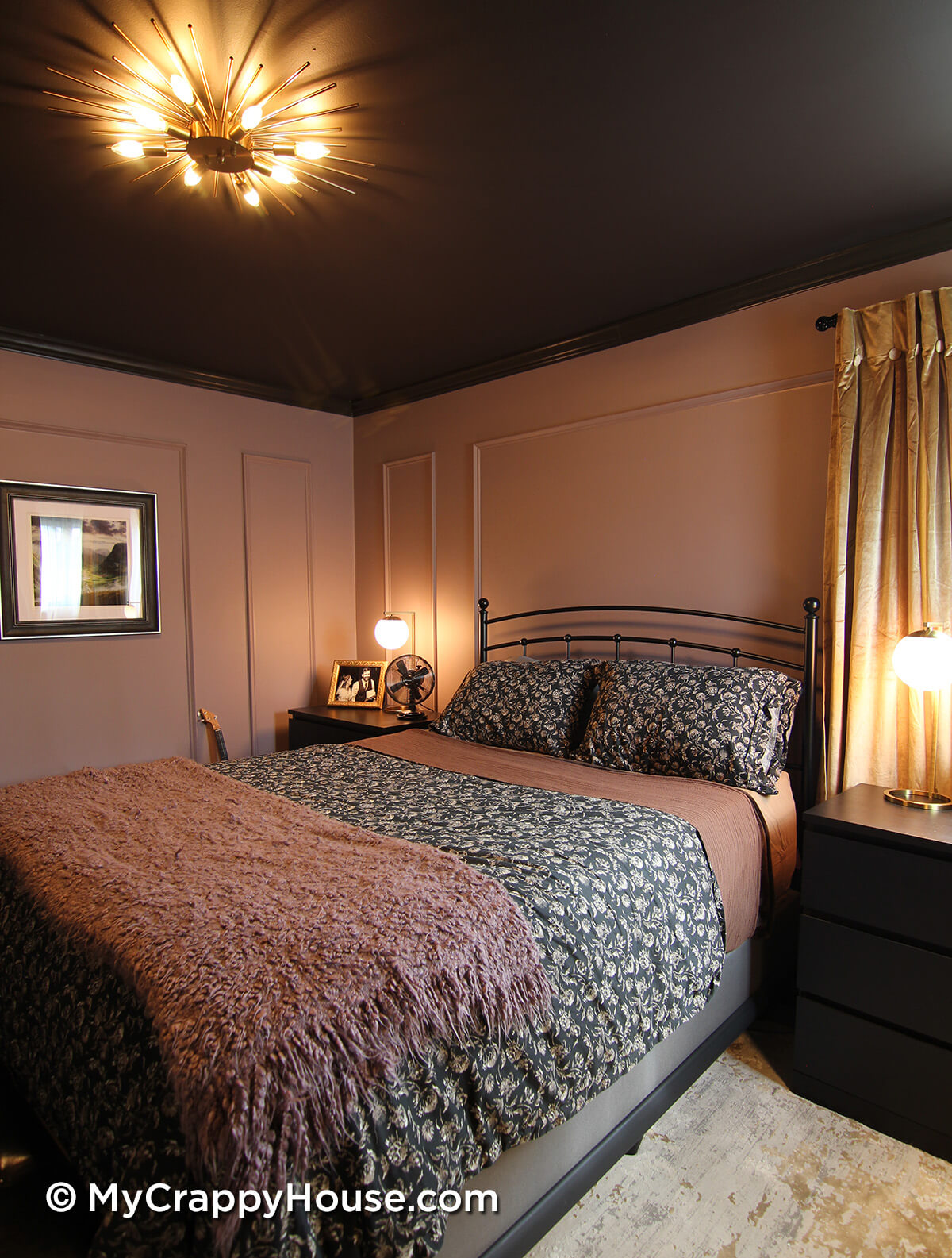 Bedroom view from opposite angle showing black metal bed, patterned bedding, dark ceiling with starburst light, mauve paneled walls, and minimalist nightstands.