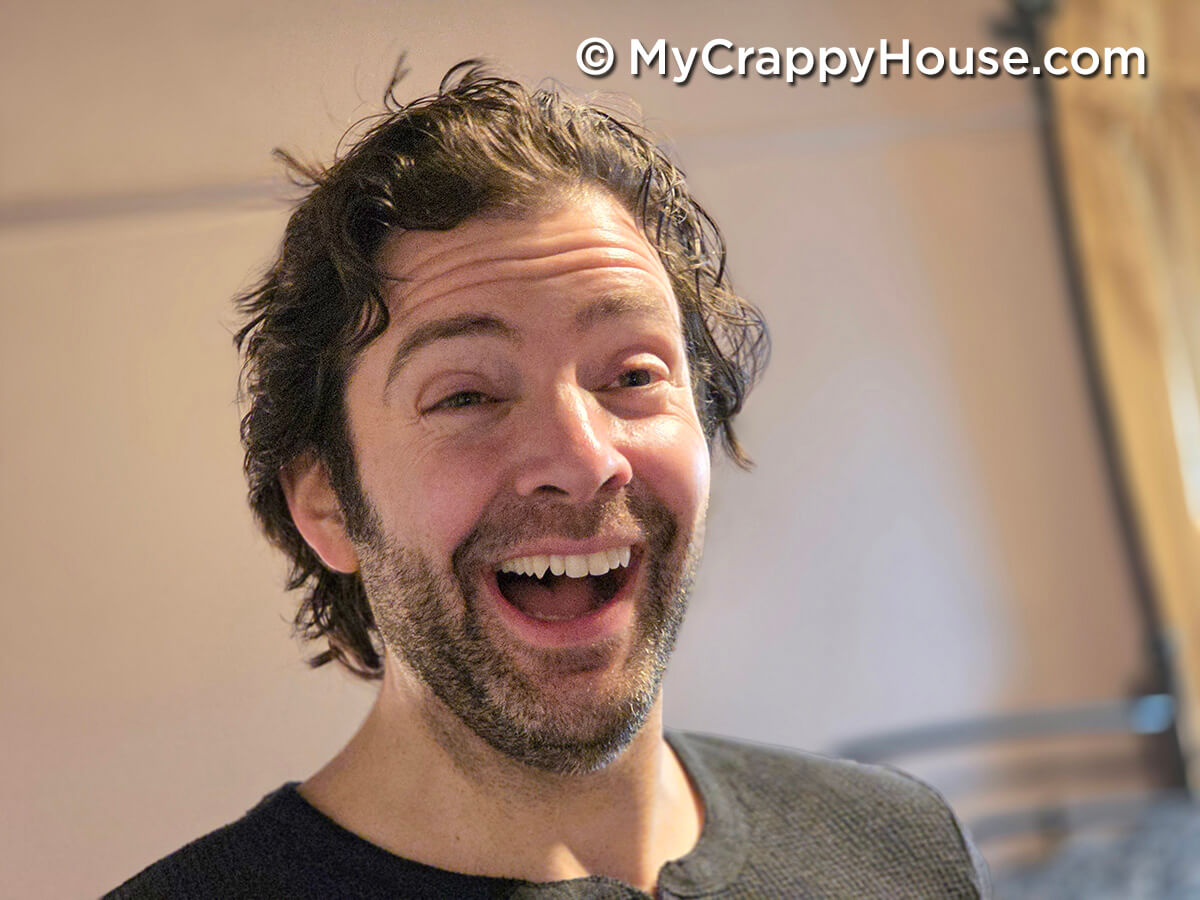 Man smiling with a delighted and impressed expression while reacting to a finished bedroom renovation reveal.