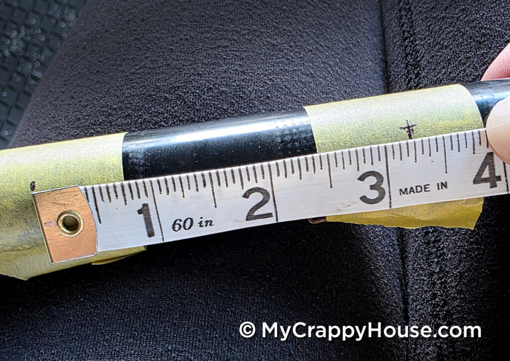 Measuring the distance between two marked hole locations on the metal seat frame with a soft measuring tape.