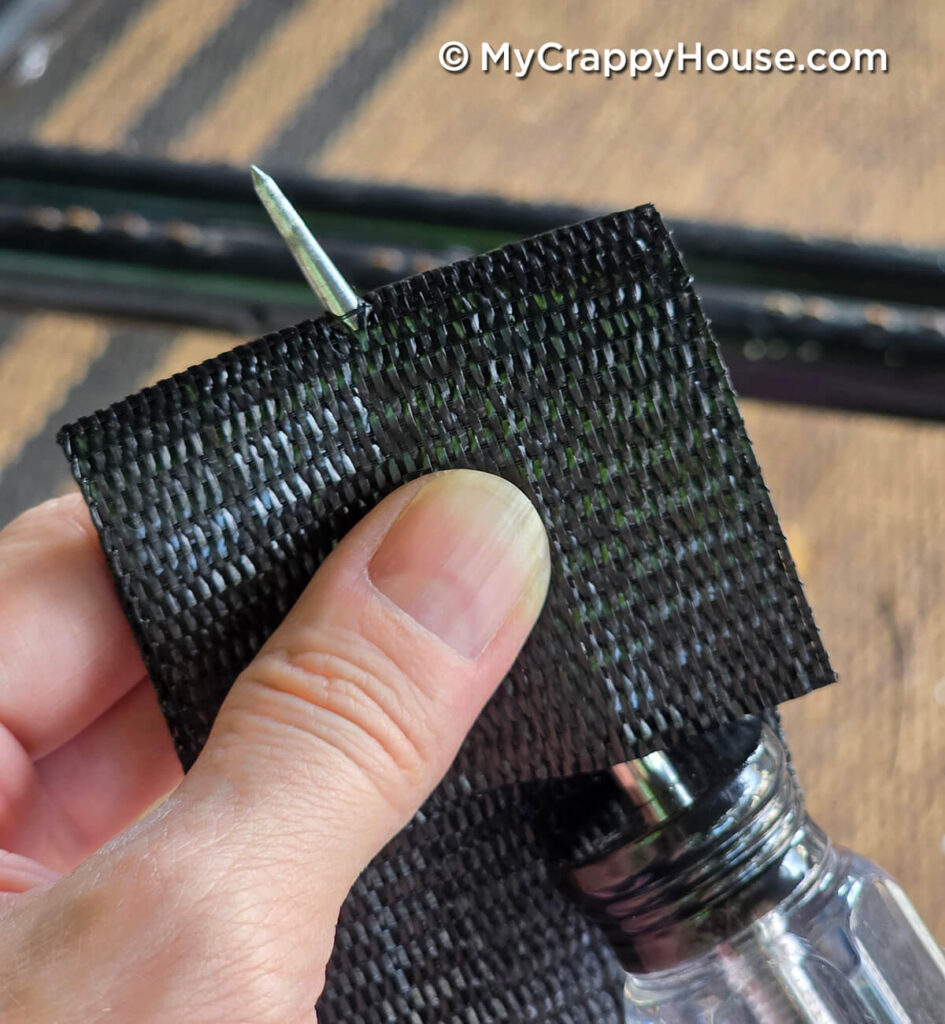 Pushing an awl through black replacement webbing near the end to make an opening for a metal clip.