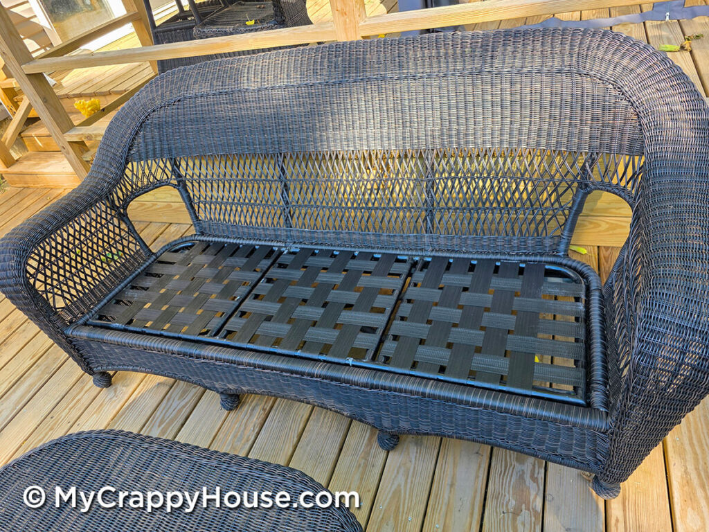 Wicker sofa with cushions removed, showing new black webbing woven tightly across all three seat sections.