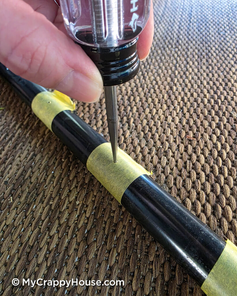 Using an awl to make a starter indentation in the metal seat frame through masking tape before drilling.