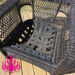 Wicker patio chair with its cushion removed, exposing sagging black elastic webbing woven across the metal seat frame.
