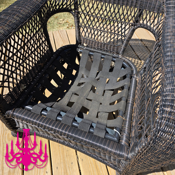 Wicker patio chair with its cushion removed, exposing sagging black elastic webbing woven across the metal seat frame.